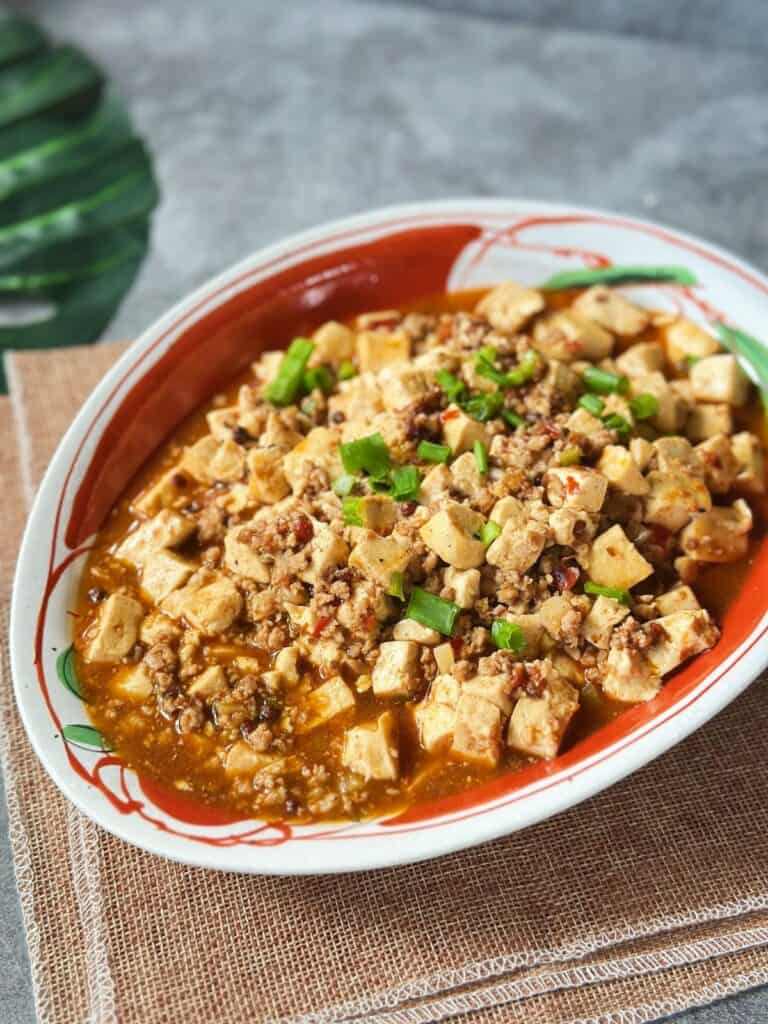 Mapo Tofu – Das Klassische Originalrezept Mapo Tofu served in a shallow bowl, coated in a glossy, spicy doubanjiang sauce with Sichuan pepper flakes.
