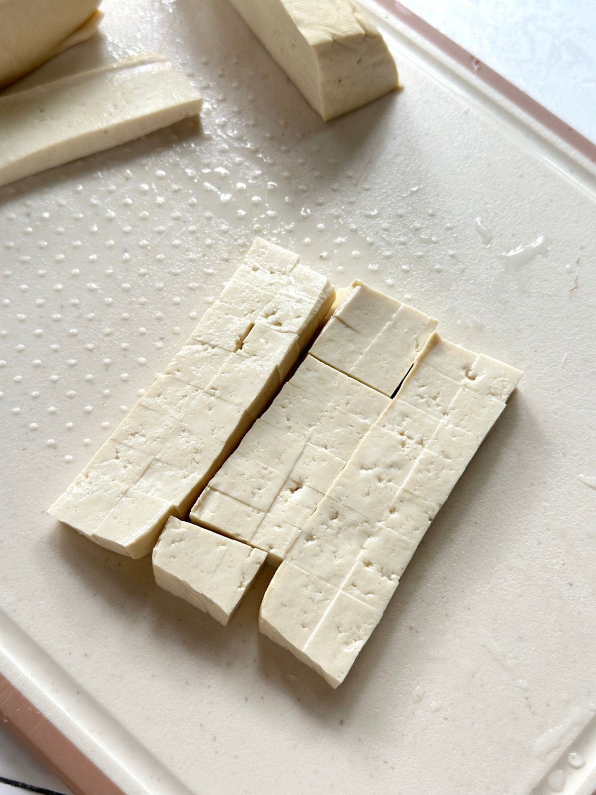 Soft tofu cut into evenly sized cubes on a cutting board.
