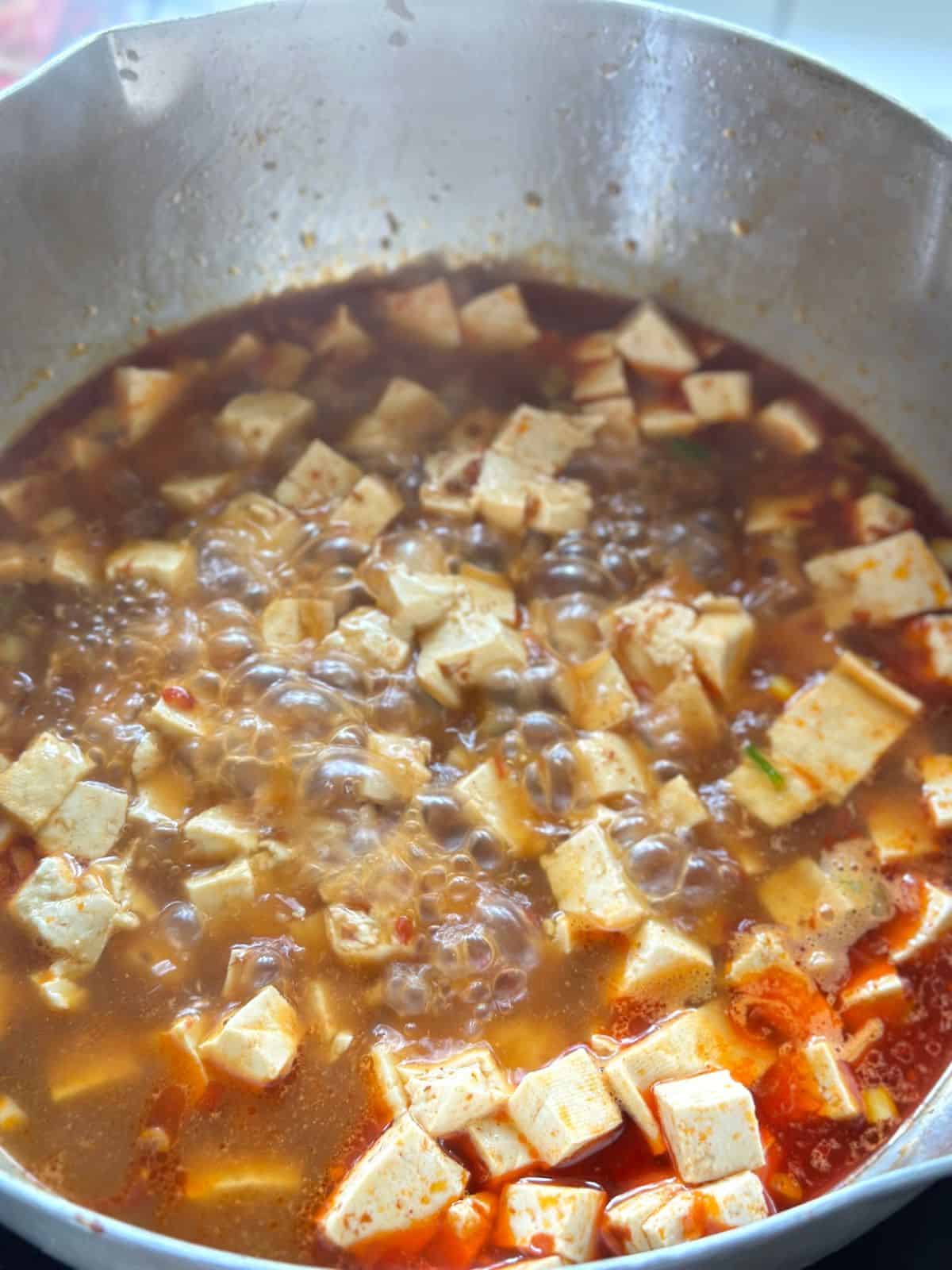 Soft tofu cubes simmering in a rich red Mapo Tofu sauce.