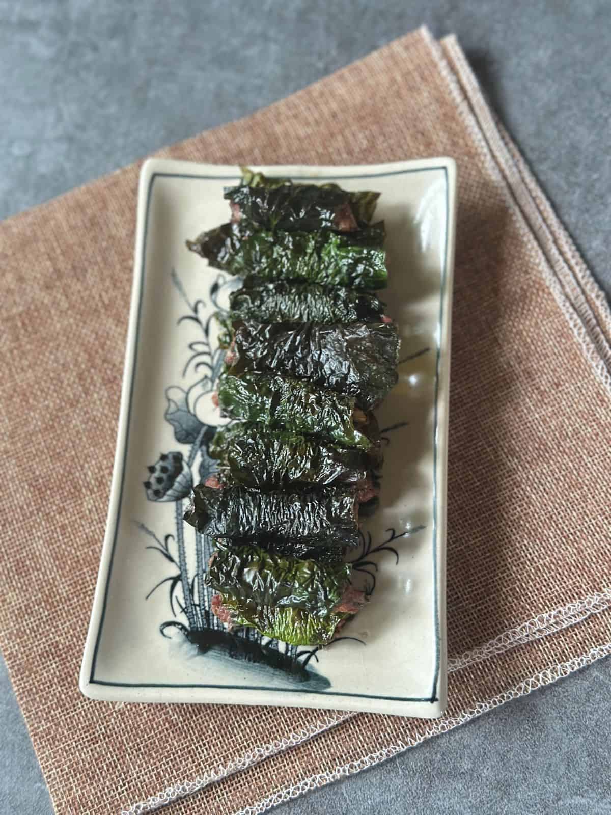 Grilled bo la lot—juicy beef wrapped in wild betel leaves—arranged on a plate.
